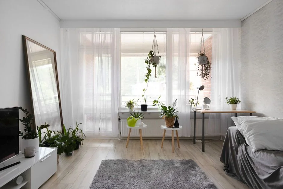 A couple wrapping furniture in a bright apartment, preparing to move.